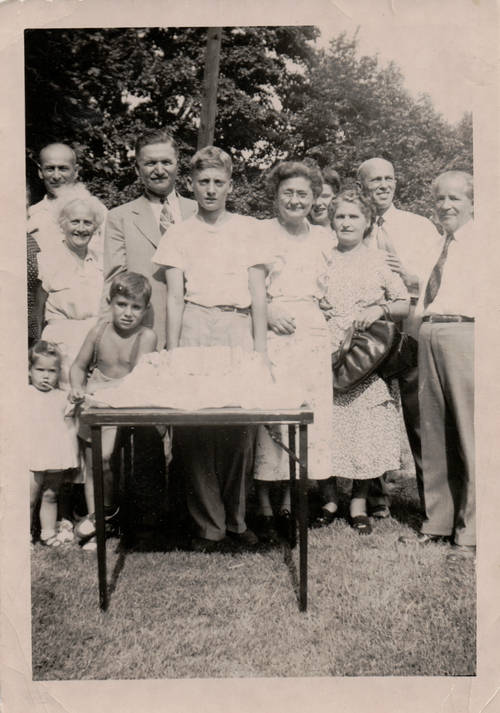 large family stands outside on a hot, sunny day. The photo is old and black and white.