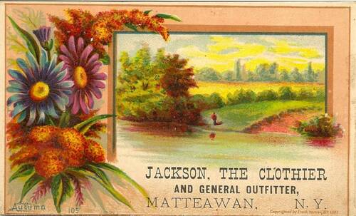 The business card depicts a pastoral landscape with a green hill and dirt path leading down to a river or lake. A small figure in a red top and blue pants stands by the water’s edge. Framing this picture is a spray of flowers, blue, purple and gold. The words “JACKSON, THE CLOTHIER, AND GENERAL OUTFITTER/MATTEAWAN, NY” are on the bottom of the card in all caps.